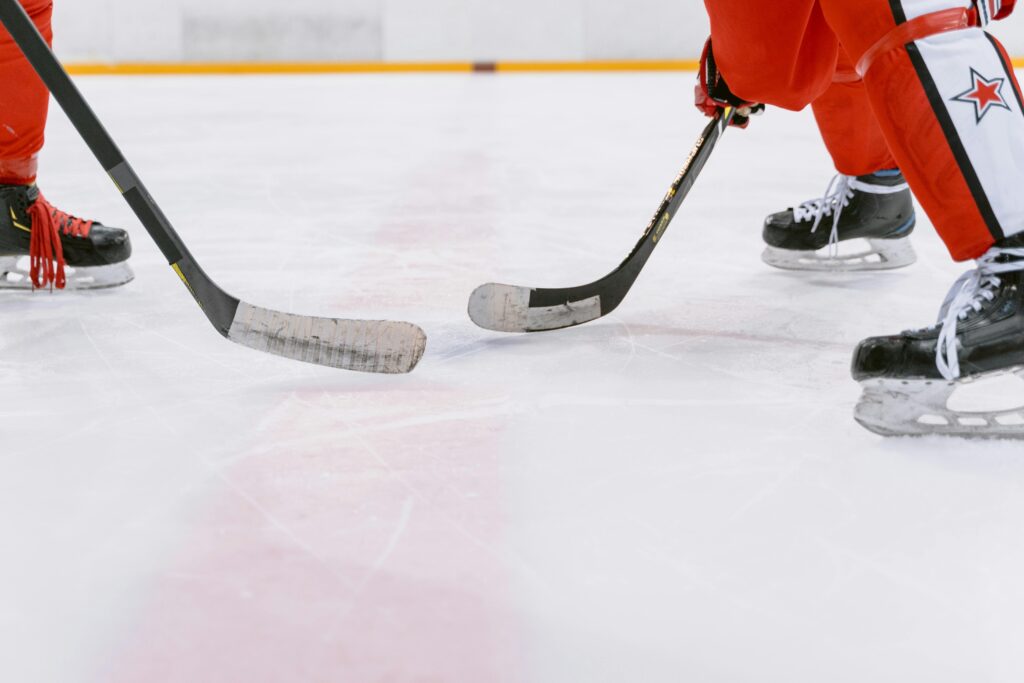 pexels-photo-6847281-6847281 Intense close-up action of ice hockey players competing indoors, focusing on their sticks and skates.